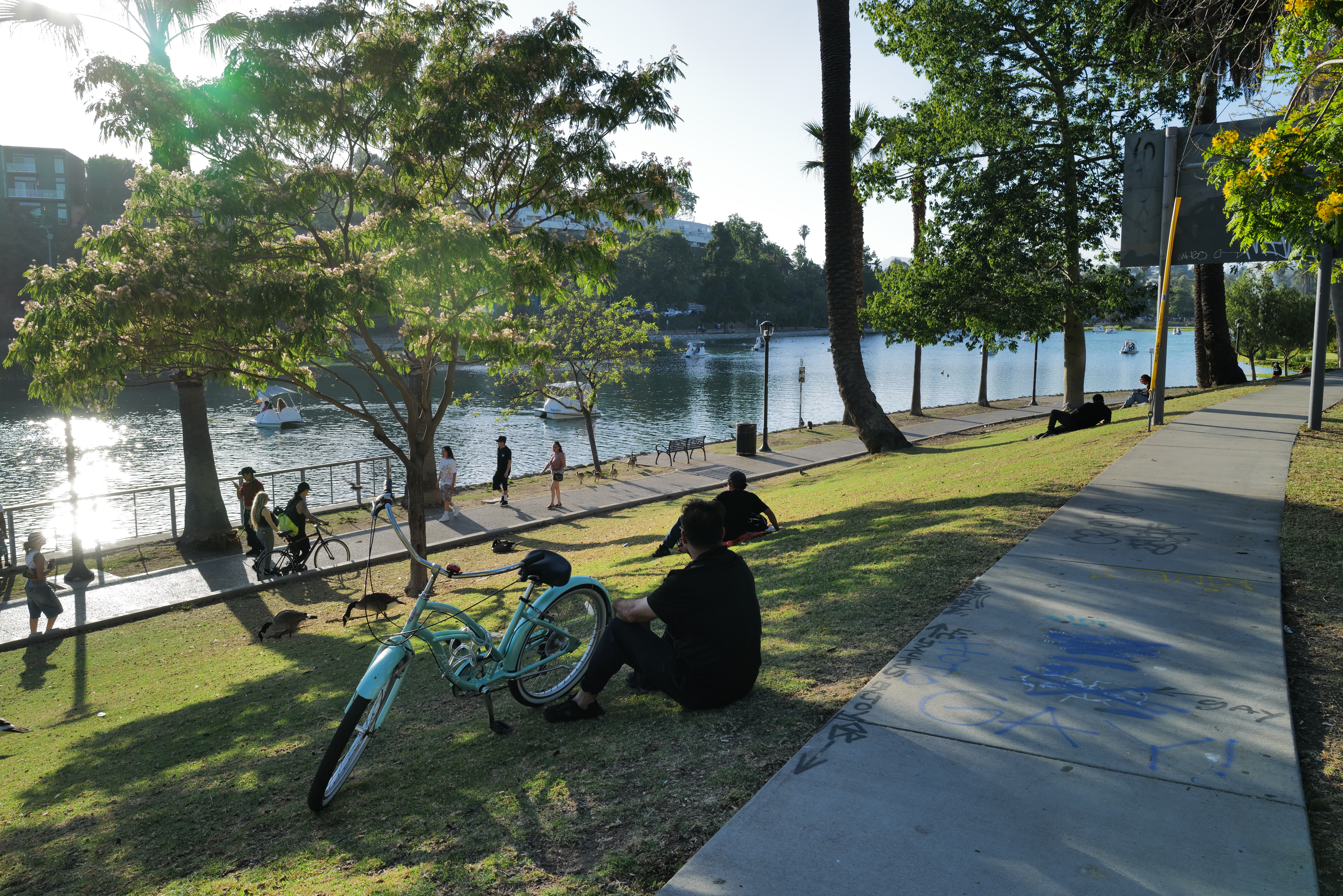 People resting beside a lake with a bicycle in the foreground.