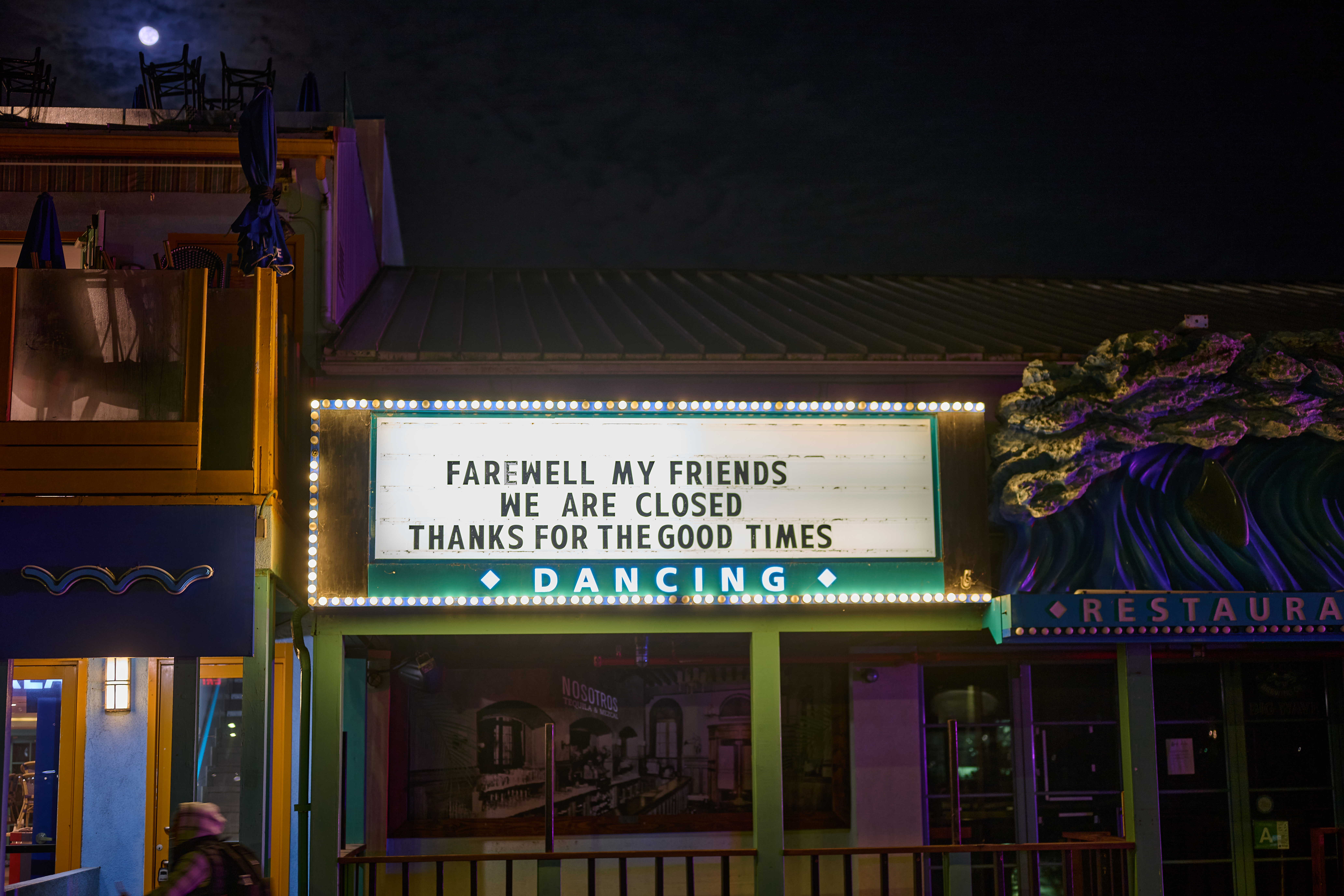 A closed venue at night displaying a farewell message on its illuminated sign.
